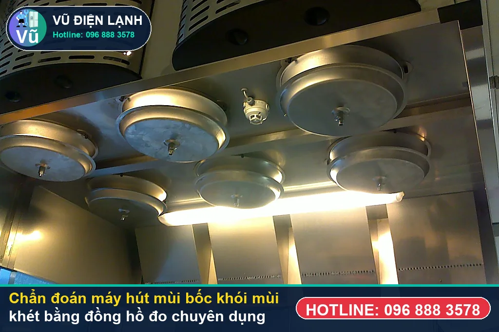 Thợ Vũ Điện Lạnh dùng đồng hồ vạn năng đo kiểm mô-tơ tuabin, tụ đề và bo mạch khi xử lý máy hút mùi bốc khói mùi khét