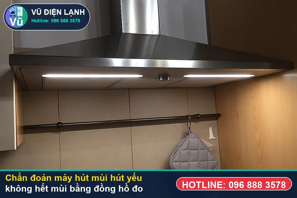 Thợ Vũ Điện Lạnh dùng đồng hồ vạn năng đo kiểm mô-tơ tuabin, tụ đề và bo mạch khi xử lý máy hút mùi hút yếu không hết mùi